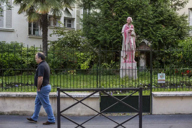 A man walks past a statue of Voltaire, a leading thinker and writer of the French Enlightenment, who owed part of his fortune to colonial-era trade, Monday, June 22, 2020. Two statues related to France's colonial era were covered in graffiti Monday amid a global movement to take down monuments to figures tied to slavery or colonialism. (Photo by Rafael Yaghobzadeh/AP Photo)