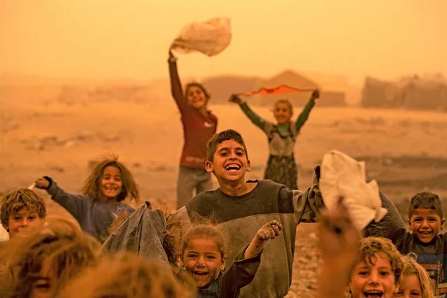 Children play amid a sandstorm at the Sahlah al-Banat camp for displaced people in the countryside of Raqa in northern Syria on October 17, 2022. (Photo by Delil Souleiman/AFP Photo)