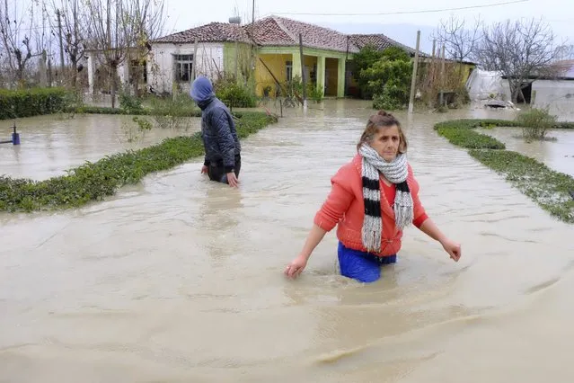 A woman and his son leave from their flooded home after heavy rainfall in the village of Hasan, about 25 kilometers (15 miles) north of Tirana, Friday, December 1, 2017. At least one person has died during heavy rainfall that flooded many parts of Albania, paralyzing its ports and causing flights from its only international airport to be suspended, authorities said Friday. (Photo by Hektor Pustina/AP Photo)