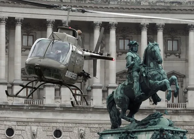 An Austrian army Bell OH-58 “Kiowa” helicopter hovers next to a statue of Prince Eugene of Savoy as it lands in Vienna October 20, 2014. (Photo by Heinz-Peter Bader/Reuters)