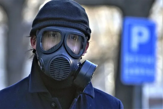 A man wearing a gas mask walks on a street in Beijing, Tuesday, December 13, 2022. Some Chinese universities say they will allow students to finish the semester from home in hopes of reducing the potential of a bigger COVID-19 outbreak during the January Lunar New Year travel rush. (Photo by Andy Wong/AP Photo)