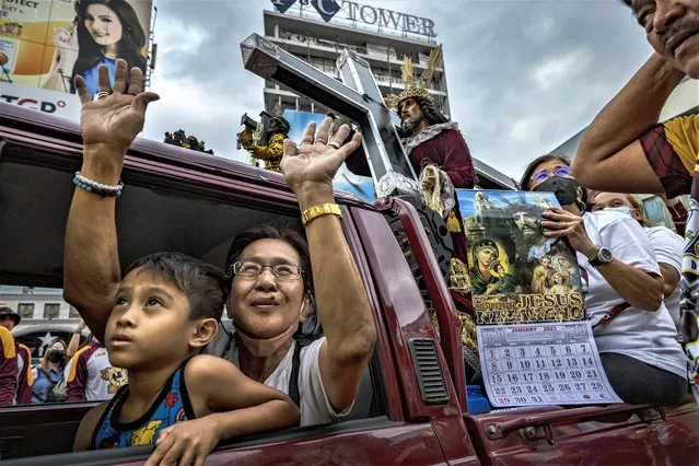 Filipino Catholic devotees jubilate as they are doused with holy water, during a parade of Black Nazarene replicas ahead of the Feast of the Black Nazarene, outside Quiapo Church on December 27, 2022 in Manila, Philippines. The Feast of the Black Nazarene usually culminates in a day long procession on January 9, as millions of barefoot devotees march to see and touch the image of the Black Nazarene. Authorities have decided to cancel the raucous procession for a third straight year as a precaution against COVID-19, and church officials are instead holding a walk of faith and novena masses on the Feast Day. The Black Nazarene is a dark wood sculpture of Jesus brought to the Philippines in 1606 from Spain and is considered miraculous by Filipino devotees. (Photo by Ezra Acayan/Getty Images)