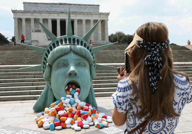A visitor takes a photo of an art installation titled “Lady Liberty's Mouth of America”, a campaign by supplement company Vimergy, aimed at sparking conversation in the nation's capital about focusing on preventive health and an end to the alleged over-reliance on prescription drugs, in front of the Lincoln Memorial in Washington, D.C., U.S., June 25, 2025. (Photo by Kevin Lamarque/Reuters)