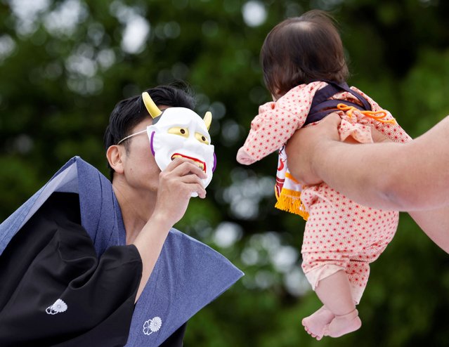 A ring assistant holds a mask to scare a baby held up by an amateur sumo wrestler during “Nakizumo” or a baby-crying sumo contest, where two wrestlers hold a baby each and a referee makes faces and loud noises to make them cry to determine the winner based on the loudest baby, at Senso-ji temple in Tokyo, Japan, on April 26, 2025. The ritual is believed to aid the healthy growth of the children and ward off evil spirits. (Photo by Manami Yamada/Reuters)
