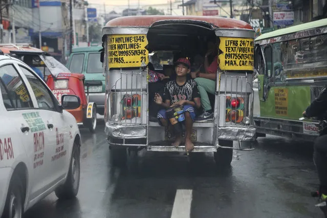 In this October 6, 2017, photo, a passenger plays a makeshift drum as he rides a jeepney in the rain in Manila, Philippines. (Photo by Aaron Favila/AP Photo)