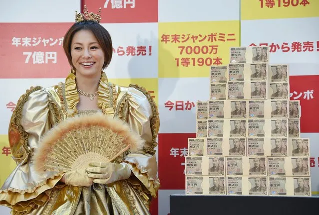 Japanese actress Ryoko Yonekura smiles beside 700 million yen (6 million USD) in cash corresponding the first prize of the “Year-end Jumbo Lottery” as the first tickets go on sale in Tokyo on November 21, 2014. Thousands of people queued up for tickets in the hope of becoming a millionaire in the annual lottery. (Photo by Toru Yamanaka/AFP Photo)