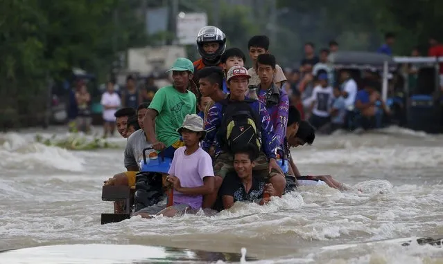 Residents ride on a farm tractor amidst a strong current along a flooded highway in Zaragoza, Nueva Ecija in northern Philippines October 20, 2015, after the province was hit by Typhoon Koppu. (Photo by Erik De Castro/Reuters)