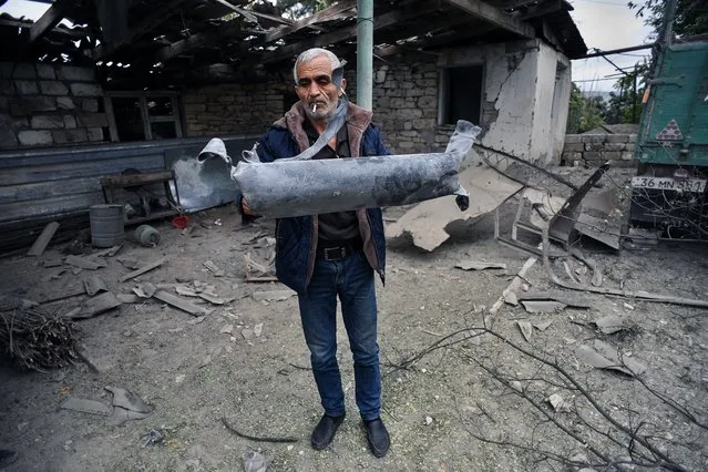 A man shows a shell fragment in the yard of his brother's house damaged by shelling during fighting between Armenia and Azerbaijan over the breakaway Nagorny Karabakh region, in the disputed region's city of Martuni on October 1, 2020. (Photo by AFP Photo/Stringer)
