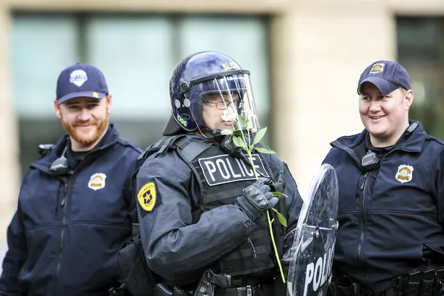 An officer smells a flower that a protestor gave him after the protest downtown against President Donald Trump during his visit to the State Capital in Salt Lake on Monday, December 4, 2017. Trump on Monday took the rare step of scaling back two sprawling national monuments in Utah, declaring that “public lands will once again be for public use” in a move cheered by Republican leaders who lobbied him to undo protections they considered overly broad. (Photo by Adam Fondren/The Deseret News via AP Photo)