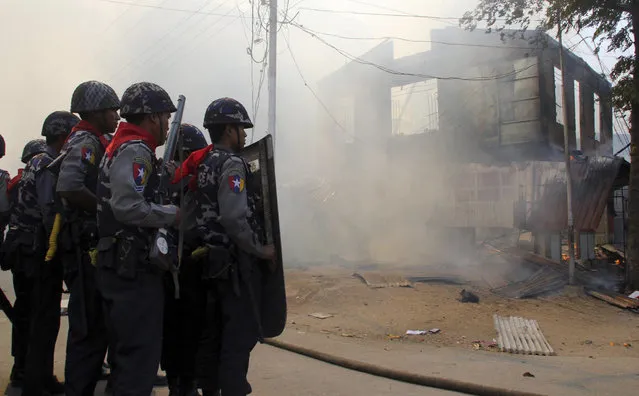 In this Thursday, March. 21, 2013 photo, armed Myanmar police oficers provide security around a smoldering building following ethnic unrest between Buddhists and Muslims in Meikhtila, Mandalay division, about 550 kilometers (340 miles) north of Yangon, Myanmar. Burning fires from two days of Buddhist-Muslim violence that killed at least 20 people smoldered across a central Myanmar town Friday as residents cowered indoors amid growing fears the country's latest bout of sectarian bloodshed could spread. The government's struggle to contain the unrest in Meikhtila is proving another major challenge President Thein Sein's reformist administration as it attempts to chart a path to democracy after nearly half a century of military rule that once crushed all dissent. (Photo by AP Photo)