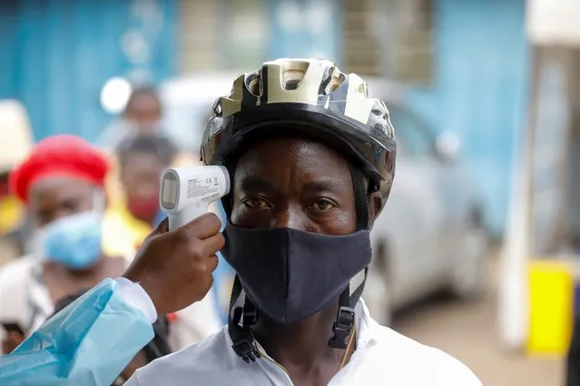 A health worker measures the temperature of a man during free mass testing for the coronavirus disease (COVID-19) in Kibera slums of Nairobi, Kenya, October 17, 2020. (Photo by Baz Ratner/Reuters)