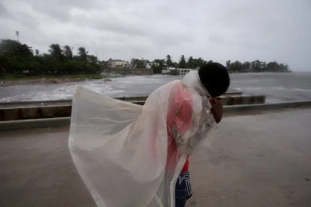 A boy covers himself with a raincoat as he walks along a pier ahead of Hurricane Matthew in Les Cayes, Haiti, October 3, 2016. (Photo by Andres Martinez Casares/Reuters)