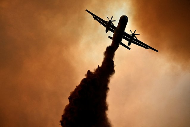 This photograph shows a canadair of the French civil security droping fire retardant over a wildfire near Fontjoncouse, southwestern France, on August 6, 2025. A wildfire has killed one person and injured nine others, scorching 11,000 hectares as firefighters work to contain the blaze, local officials said. The fire, which started the day before, has destroyed or damaged 25 homes in the southern Aude department, where more than 1,800 firefighters have been battling to control what is now the largest wildfire in France this summer. (Photo by Lionel Bonaventure/AFP Photo)