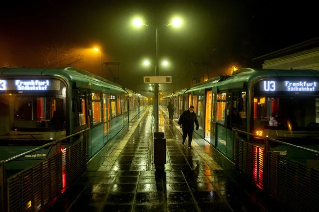 A woman walks away from a subway station in Oberursel near Frankfurt, Germany, on a rainy Thursday, November 12, 2020, as the numbers of new Coronavirus infections went over 20 000 again. (Photo by Michael Probst/AP Photo)