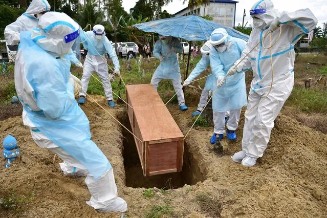 Workers wearing personal protective equipment (PPE) bury a civilian defence volunteer who died from Covid-19 coronavirus at Ban Yakang cemetery in the southern Thai province of Narathiwat on February 24, 2022. (Photo by Madaree Tohlala/AFP Photo)