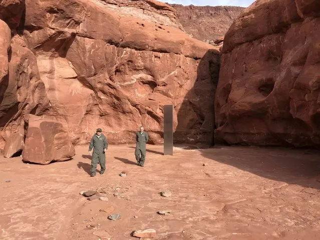 Utah Department of Public Safety Aero Bureau and Utah Division of Wildlife Resources crew members walk near a metal monolith they discovered in a remote area of Red Rock Country in Utah, U.S. November 18, 2020. According to a statement by DPS, Utah officials have discovered a monolith of unknown origin in the wild. The mystery surrounding a metal monolith found in the middle of the Utah desert deepened today (Nov. 30) after it apparently vanished. Utah's Bureau of Land Management said it had seen credible reports the object had been removed “by an unknown party”.(Photo by Utah Department of Public Safety via Reuters)