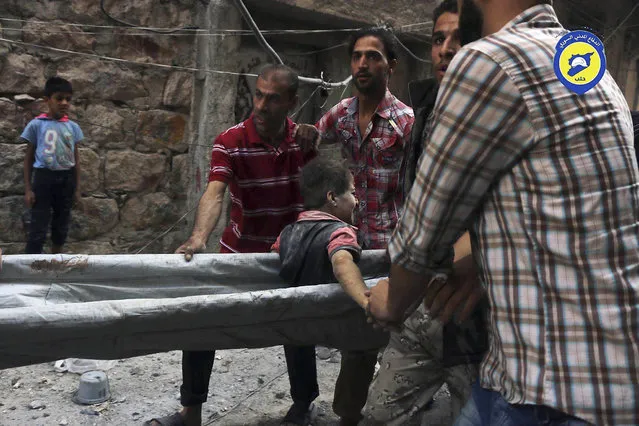 In this picture taken, Tuesday, October 11, 2016, provided by the Syrian Civil Defense group known as the White Helmets, Syrian Civil Defense workers take out a boy, alive, from the rubble, in rebel-held eastern Aleppo, Syria. (Photo by Syrian Civil Defense- White Helmets via AP Photo)