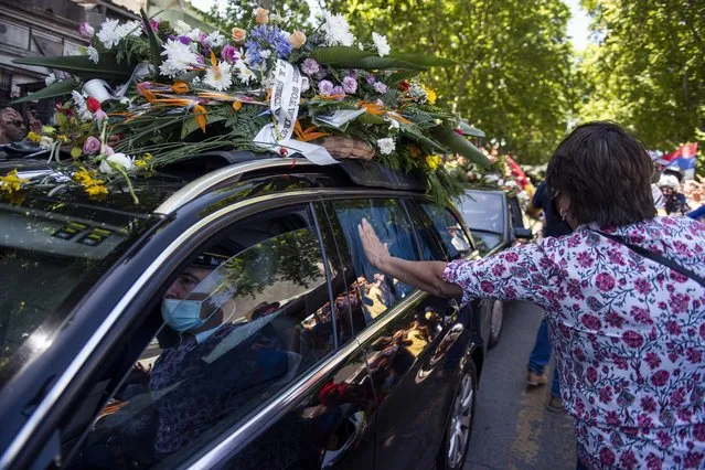 Mourners touch the hearse carrying the casket of former Uruguayan President Tabare Vazquez heads to the cemetery in Montevideo, Uruguay, Sunday, December 6, 2020. The former president died at his home in Montevideo early Sunday. (Photo by Matilde Campodonico/AP Photo)