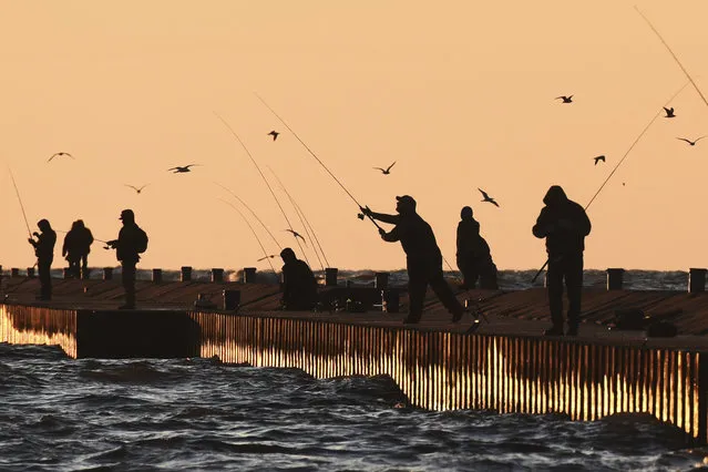 The setting sun reflects off the south pier and Lake Michigan as fishermen try their luck, Monday, March 27, 2023, in St. Joseph, Mich. (Photo by Don Campbell/The Herald-Palladium via AP Photo)