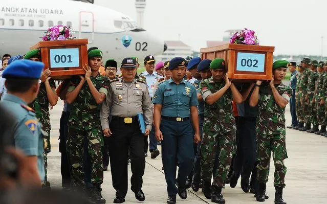 Indonesian soldiers carry coffins containing victims of the AirAsia flight QZ8501 crash at the Indonesian Air Force Military Base Operation Airport on December 31, 2014 in Surabaya, Indonesia. A massive recovery operation has begun following confirmation from Indonesian officials that remains and debris found in waters off Borneo are from the missing AirAsia plane.  (Photo by Robertus Pudyanto/Getty Images)