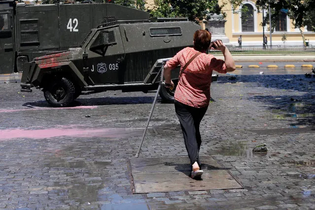 A woman using a crutch prepares to throw a stone toward a riot police vehicle during a strike against the national pension system in Santiago, Chile, November 4, 2016. (Photo by Carlos Vera/Reuters)