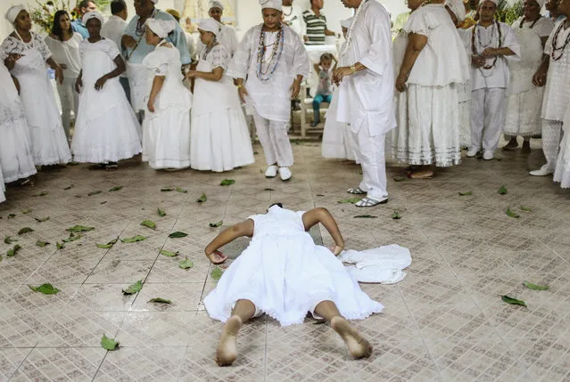 A worshipper lies on the floor during a Candomble ceremony honoring goddesses Iemanja and Oxum on December 12, 2015 in Itaborai, Brazil. Candomble is an Afro-Brazilian religion whose practitioners sometimes fall into trances during ceremonies believing they have become possessed by gods, or orixas. The roots of the Candomble religion came to Brazil via African slaves and eventually incorporated some elements of Catholicism. Afro-Brazilian religions generally refer to Iemanja as goddess of the sea and Oxum as goddess of rivers, lakes and waterfalls, or fresh water. (Photo by Mario Tama/Getty Images)