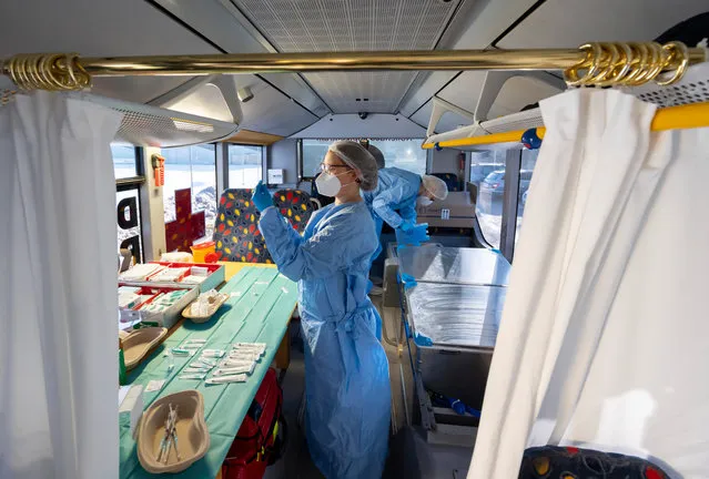 Nurses Annett Goebel and Bernadett Laub prepare doses of the Pfizer/BioNTech Comirnaty vaccine at a mobile vaccination center situated in a modified bus in Grosshartmannsdorf, Germany, February 21, 2021. The state of Saxony is testing several mobile vaccination units, including the converted bus as well as truck-pulled trailers, in an effort to better reach rural communities that might otherwise be far from one of the state's mass vaccination centers. (Photo by Matthias Rietschel/Getty Images)
