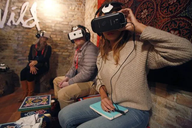 Members of the media try earphones and a headset used for virtual reality at the Sundance Film Festival in Park City, Utah January 23, 2015. The content is viewed on a wraparound-style headset that project a 360-degree panorama, giving viewers the feel of being in the action. (Photo by Jim Urquhart/Reuters)