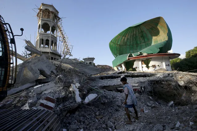 A resident inspects a mosque damaged by an earthquake in North Lombok, Indonesia, Tuesday, August 7, 2018. Thousands left homeless by the powerful quake that ruptured roads and flattened buildings on the Indonesian tourist island of Lombok sheltered Monday night in makeshift tents as authorities said rescuers hadn't yet reached all devastated areas. (Photo by Tatan Syuflana/AP Photo)