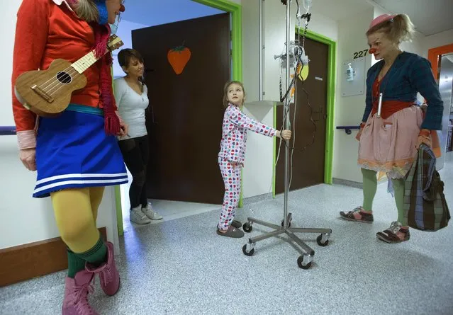 Malena, 7, looks at Belgian clowns Jupette (L) and Lili Bellule at the pediatric department of the Hopital Erasme at the Universite Libre de Bruxelles (ULB), in Brussels January 27, 2015. (Photo by Yves Herman/Reuters)