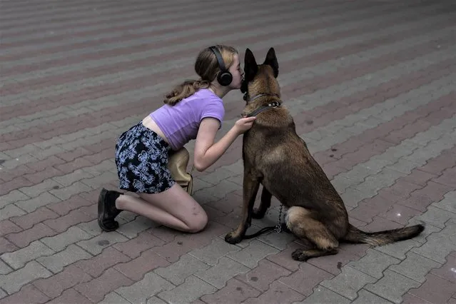 A girl kisses her dog in a park near the Odesa Transfiguration Cathedral in Odesa, Ukraine, Sunday, July 23, 2023. (Photo by Jae C. Hong/AP Photo)