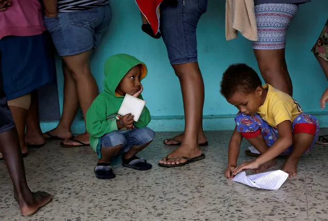 Two children play while their parents line up for clothes at school used as a shelter as storm Otto approaches in Guapiles, Costa Rica November 23, 2016. (Photo by Juan Carlos Ulate/Reuters)