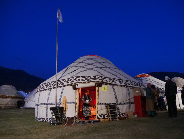 A woman leaves her yurt with a pile of dishes as the games' attendees settle in for the night in the chilly mountain venue. (Photo by Amos Chapple/Radio Free Europe/Radio Liberty)