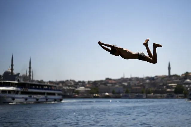 A youngster dives into the Bosphorus next to the Golden Horn during a hot summer day in Istanbul, Turkey, Wednesday, July 19, 2023. (Photo by Francisco Seco/AP Photo)