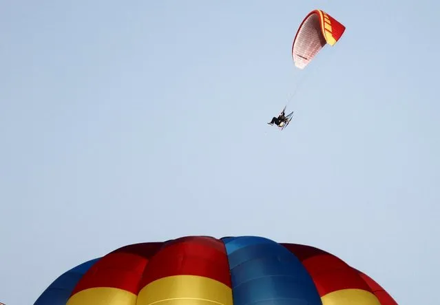 A paraglider floats above a balloon, as it takes part in the 36th Italian International Balloon Grand Prix in Gualdo Cattaneo, near Perugia, Italy on July 29, 2023. (Photo by Yara Nardi/Reuters)