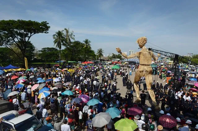 Residents watch an eight-metre tall wicker puppet from the French cultural group L'Homme Debout parade in Yangon city's Dala township on December 2, 2016 to mark the opening of the Mingalabar Festival. The three-day long festival held in celebration of the 55th anniversary of French-Myanmar relations, gathers local and international artists from street art, music, circus and dance that will bring street festivities around Yangon's public areas. (Photo by Romeo Gacad/AFP Photo)
