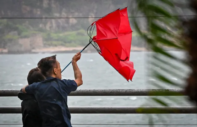 People struggle with their umbrella in high winds brought by Super Typhoon Saola in Heng Fa Chuen in Hong Kong on September 1, 2023. (Photo by Mladen Antonov/AFP Photo)