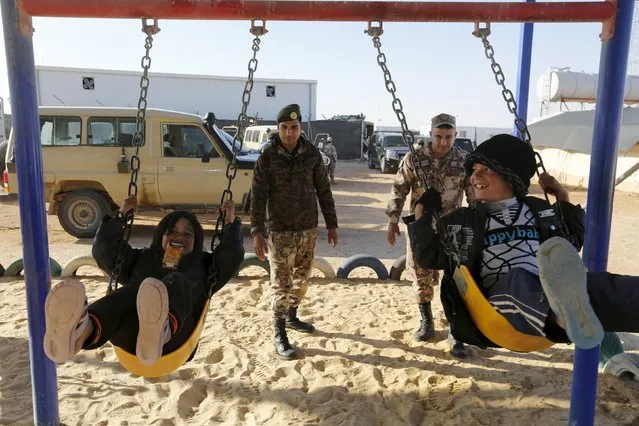 Jordanian solders play with Syrian refugee children after they crossed into Jordanian territory with their families, near the town of Ruwaished, at the Hadalat area, east of the capital Amman, January 14, 2016. After months of being stranded at the border, a group of Syrian refugees has finally been allowed to enter Jordan. Jordanian authorities say they have to address  security concerns before allowing more refugees into the country burdened with over 1.4 million refugees, said the commander of Jordan's border guard force, Brigadier General Saber Mahayrah. (Photo by Muhammad Hamed/Reuters)