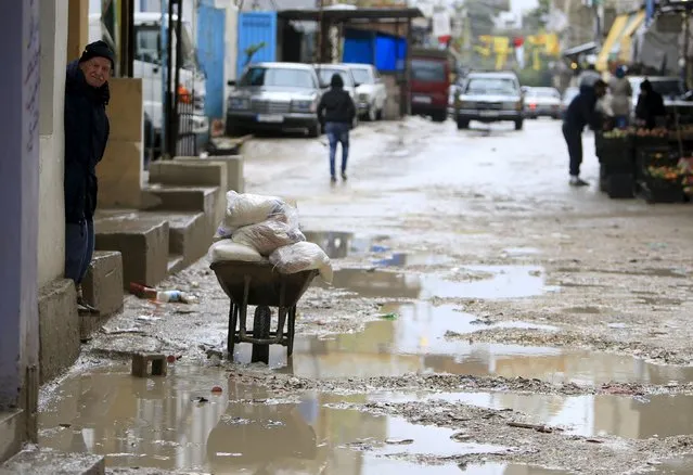 A man looks out of a doorway near water puddles in Ain al-Hilweh Palestinian refugee camp, near the port-city of Sidon, southern Lebanon January 19, 2016. (Photo by Ali Hashisho/Reuters)