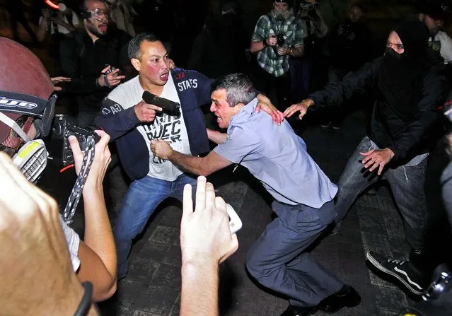 An undercover police officer rescues a police colonel from demonstrators of the Free Pass Movement during clashes in Sao Paulo, on Oktober 25, 2013. The MPL was demonstrating to demand zero tariffs in the public transportation system. (Photo by Inacio Teixeira/Reuters)