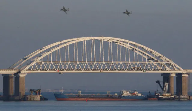 Russian jet fighters fly over a bridge connecting the Russian mainland with the Crimean Peninsula with a cargo ship beneath it after three Ukrainian navy vessels were stopped by Russia from entering the Sea of Azov via the Kerch Strait in the Black Sea, Crimea on November 25, 2018. (Photo by Pavel Rebrov/Reuters)