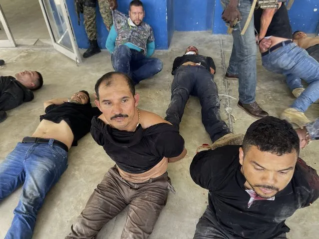 Suspects in the assassination of Haiti's President Jovenel Moise sit on the floor handcuffed after being detained, at the General Direction of the police in Port-au-Prince, Haiti, Thursday, July 8, 2021. A Haitian judge involved in the murder investigation said that President Moise was shot a dozen times and his office and bedroom were ransacked. (Photo by Jean Marc Hervé Abélard/AP Photo)