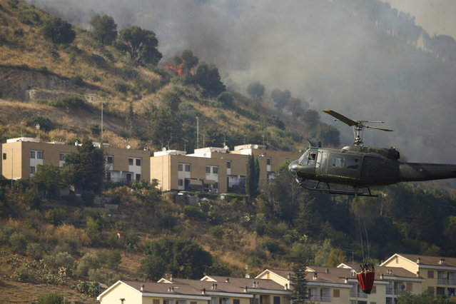 A helicopter drops water over a wildfire in the Monte Castillo area, near Tivoli, just a few miles from Rome, Friday, August 13, 2021. The southern regions of Sicily, Sardinia, Calabria and also central Italy, where temperatures are expected to reach record hights, were badly hit by wildfires. Climate scientists say there is little doubt that climate change from the burning of coal, oil and natural gas is driving extreme events, such as heat waves, droughts, wildfires, floods and storms. (Photo by Cecilia Fabiano/LaPresse via AP Photo)