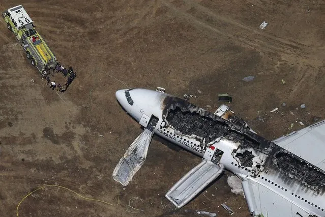 Rescue officials stand near an Asiana Airlines Boeing 777 plane after it crashed while landing at San Francisco International Airport in California July 6, 2013. (Photo by Jed Jacobsohn/Reuters)