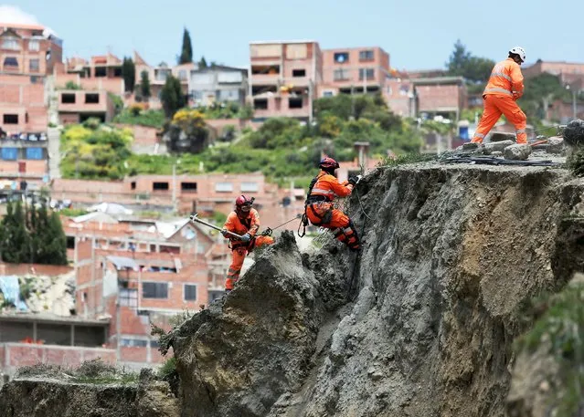 Rescue workers climb where a landslide occurred due to heavy rains in Los Rosales district in La Paz, Bolivia February 21, 2019. (Photo by David Mercado/Reuters)