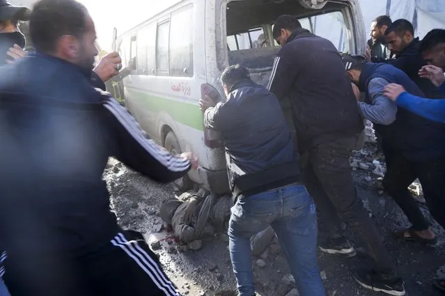 Palestinians push an ambulance to release a man at Al-Aqsa Hospital In Deir al Balah, Gaza Strip, moments after an Israeli strike hit a building next to it on Wednesday, January 10, 2024. (Photo by Hatem Moussa/AP Photo)