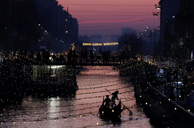Two people row a gondola nearby a bridge of the Naviglio Grande canal that was decorated with Christmas lights, in Milan, Italy on December 20, 2023. (Photo by Claudia Greco/Reuters)