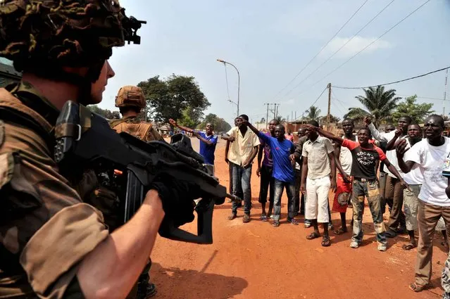 French soldiers of the Sangaris Operation come across civilian supporters of the Anti-Balaka Christian militia during a patrol in Bangui on January 25, 2014. The new president of the Central African Republic Catherine Samba Panza set to work to choose members of a government capable of ending horrific inter-religious violence and bringing order to the country. (Photo by Issouf Sanogo/AFP Photo)