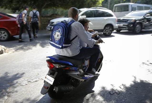 A man with his son on a scooter after the end of the school day in Beirut, Lebanon, Wednesday, September 29, 2021. This fall, Lebanon's schools have been gripped by the same chaos that has overwhelmed everything else in the country in its historic economic meltdown. The start of the academic year has been postponed repeatedly because thousands of teachers are on strike, demanding adjustments in their salary to cope with hyperinflation. (Photo by Bilal Hussein/AP Photo)