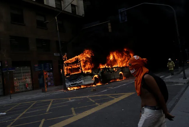 An anti-government demonstrator walks past a bus burning after a clash with riot policemen, during a protest against the Rio de Janeiro state government and a plan that will limit public spending, next to the State Assembly of Rio de Janeiro, Brazil February 1, 2017. (Photo by Ricardo Moraes/Reuters)